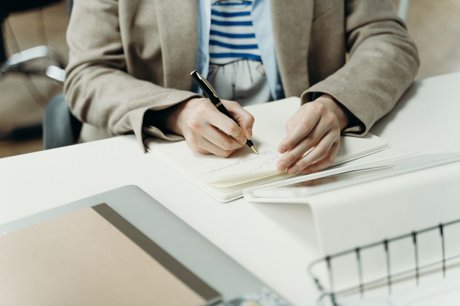 Persona escribiendo notas de planificación profesional en un escritorio moderno