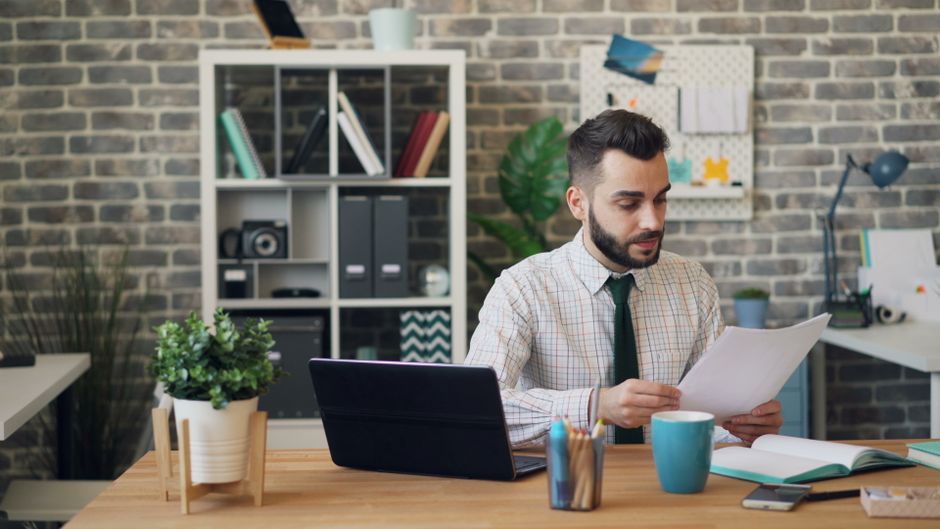 Joven leyendo documentos en escritorio
